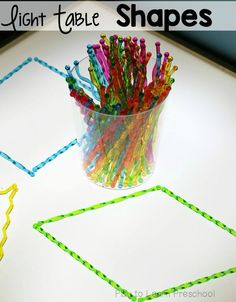 a glass filled with colored straws sitting on top of a table next to a pair of scissors