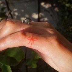 a person's hand with a ring on it and a red cross painted on their finger