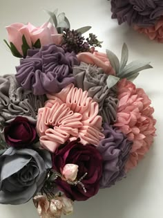 a bouquet of flowers sitting on top of a white table next to another flower arrangement