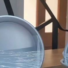 an empty bowl sitting on top of a wooden table next to a metal object with water in it