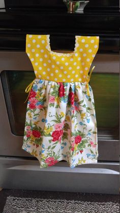 a yellow and white dress is hanging on the oven door handle in front of an oven