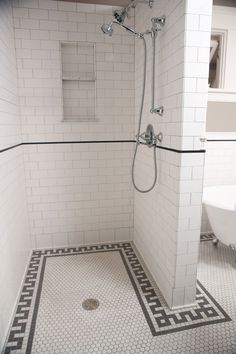 a white tiled bathroom with black and white flooring