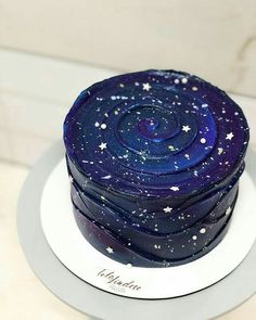 a blue cake with stars on it sitting on top of a white platter in front of a wall