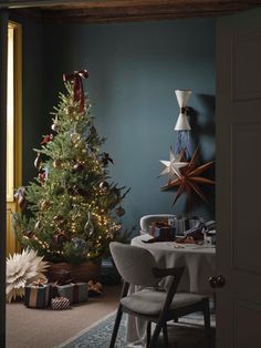 a christmas tree in the corner of a room next to a table with presents on it