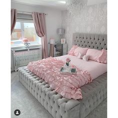 a bed with pink sheets and pillows in a room