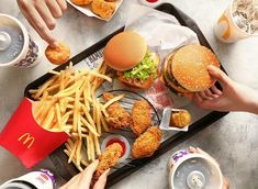 people are eating chicken and fries at a fast food restaurant with sodas on the side