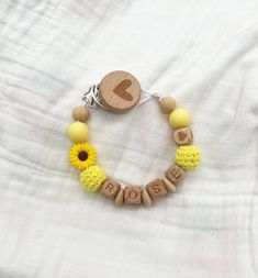 a wooden beaded bracelet with yellow beads and a heart on the clasp that says rose