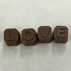 three chocolate letters spelling love on a white surface