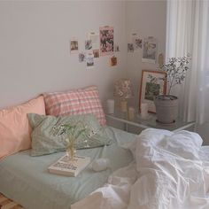 a bed with white sheets and pillows in a bedroom next to a window filled with pictures