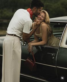 a man kissing a woman in the back of a car while standing next to her