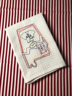 a red and white striped table cloth with an embroidered design on it