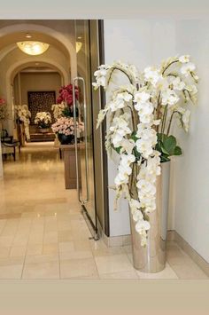 a vase with white flowers in it sitting on the floor next to a door way