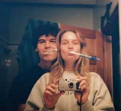 two people taking a selfie in front of a mirror with toothbrushes sticking out of their mouths