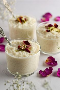 three small glasses filled with oatmeal and flowers on a table next to petals