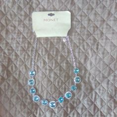 This Is A New With Tags Monet Silver Tone Necklace With Light Blue Crystal Accents. The Necklace Features A Chain With Seven Square-Shaped Crystals, Each With Smaller Crystals Around The Edges. The Necklace Is Approximately 18 Inches Long And Has A Lobster Claw Clasp. The Necklace Is Packaged In A Clear Plastic Bag With A White Card That Reads "Monet" And "Trend Table." The Necklace Is In New Condition With No Visible Imperfections. Shaped Crystals, Clear Plastic Bags, Monet Jewelry, White Card, Blue Crystals, Clear Plastic, Lobster Claw, Plastic Bag, Blue And Silver