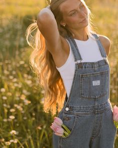 a woman standing in a field with flowers