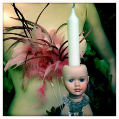 a doll with a candle and feathers on it's head