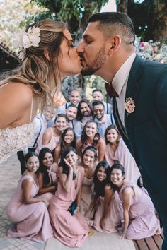 a bride and groom kissing in front of a group of people