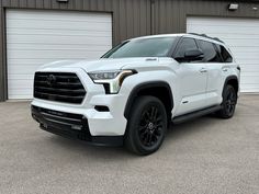 a white toyota truck parked in front of a garage with two doors on the side