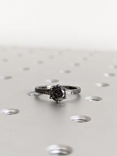 a black diamond ring sitting on top of a silver surface with drops of water around it