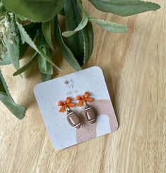 two small orange bows are attached to the back of some silver earring studs