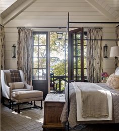 a bedroom with a four poster bed and two chairs in front of the door that leads to an outside patio