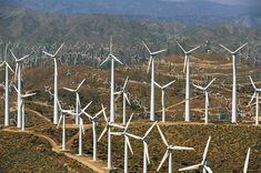 many wind mills in the desert with mountains in the background