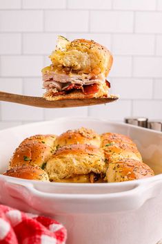 ham and cheese sliders in a white bowl with a wooden spoon on the side