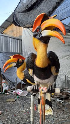 two fake birds sitting on top of each other in front of a tarp covered building