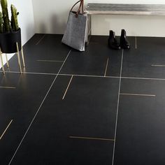 a black tile floor with gold lines on it and a white bench in the background