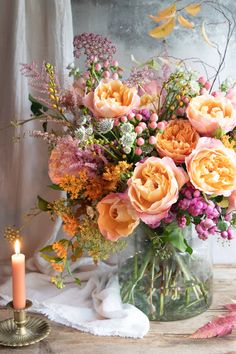 a vase filled with lots of flowers next to a lit candle