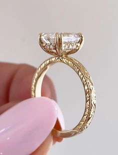 a close up of a person's hand holding a ring with a diamond on it