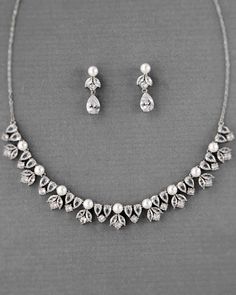 Add a little bit of luxury with this bridal set style. Created with several shapes of cubic zirconia and off-white pearls, this set is the perfect embellishment for your wedding day look. Lead, cadmium, and nickel free, rhodium plated, the necklace is 17 inches long with a 2.5 inch extender. The earrings are 1 inch long with titanium post-backs. White Sparkling Stones Jewelry Set For Wedding, White Wedding Jewelry Sets With Sparkling Stones, Pearl Bridal Earrings With Diamond Accents For Wedding, Pearl Necklace With Diamond Accents For Wedding, Bridal Pearl Earrings With Diamond Accents For Wedding, Wedding Pearl Necklace With Diamond Accents, Diamond White Pearl Necklace With Diamond Accents For Wedding, White Pearl Drop Bridal Necklace With Cubic Zirconia, Elegant Pearl Bridal Sets With Pearl Drop