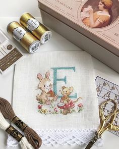 a cross stitch kit with scissors, thread and other crafting supplies next to it