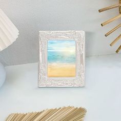 a white frame sitting on top of a table next to a vase and matchessticks