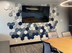 a conference room with hexagonal tiles on the wall and a flat screen tv mounted to the wall