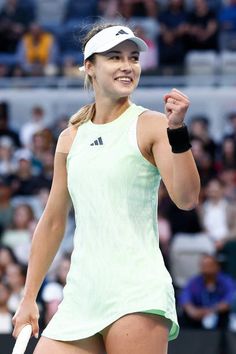 a woman holding a tennis racquet in her right hand and smiling at the camera