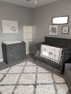 a baby's room with gray furniture and pictures on the wall, including a crib