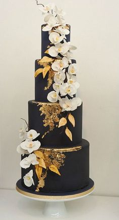 a black and gold wedding cake with white flowers