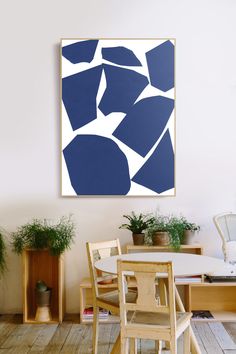 a painting hanging on the wall above a dining room table with chairs and potted plants