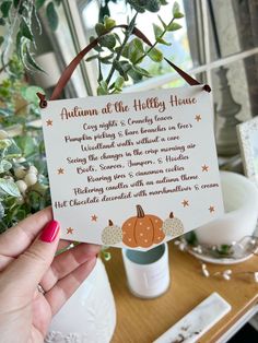 a person holding up a sign that says autumn at the holly house with pumpkins and leaves