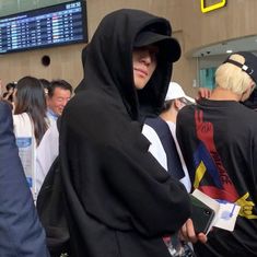 a group of people standing around each other in front of a tv screen and wearing hoods