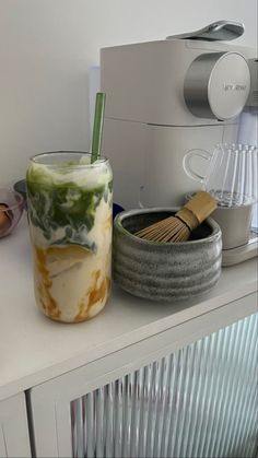 a cup that is sitting on top of a counter next to a bowl and whisk