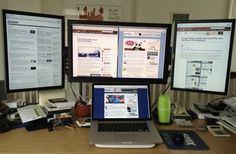 two computer monitors sitting on top of a wooden desk