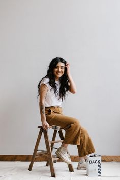 a woman sitting on top of a wooden ladder