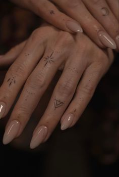 two hands with tattoos on their fingers and one has a star tattoo on the middle finger