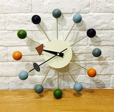 a clock that is sitting on top of a wooden table in front of a brick wall