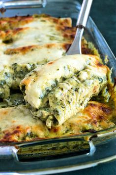 a casserole dish with spinach and cheese being scooped from the casserole