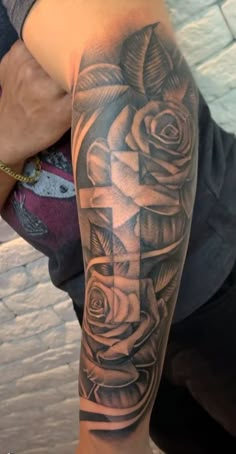 a man with a cross and roses tattoo on his arm