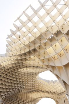 a large white structure with lots of lines on it's sides and people walking underneath